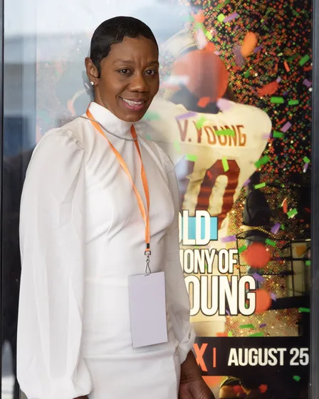 Guest in a white ensemble beside the film's poster display